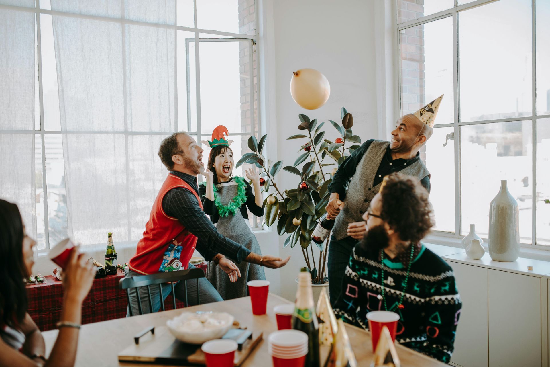 A group of people are playing with balloons at a christmas party.