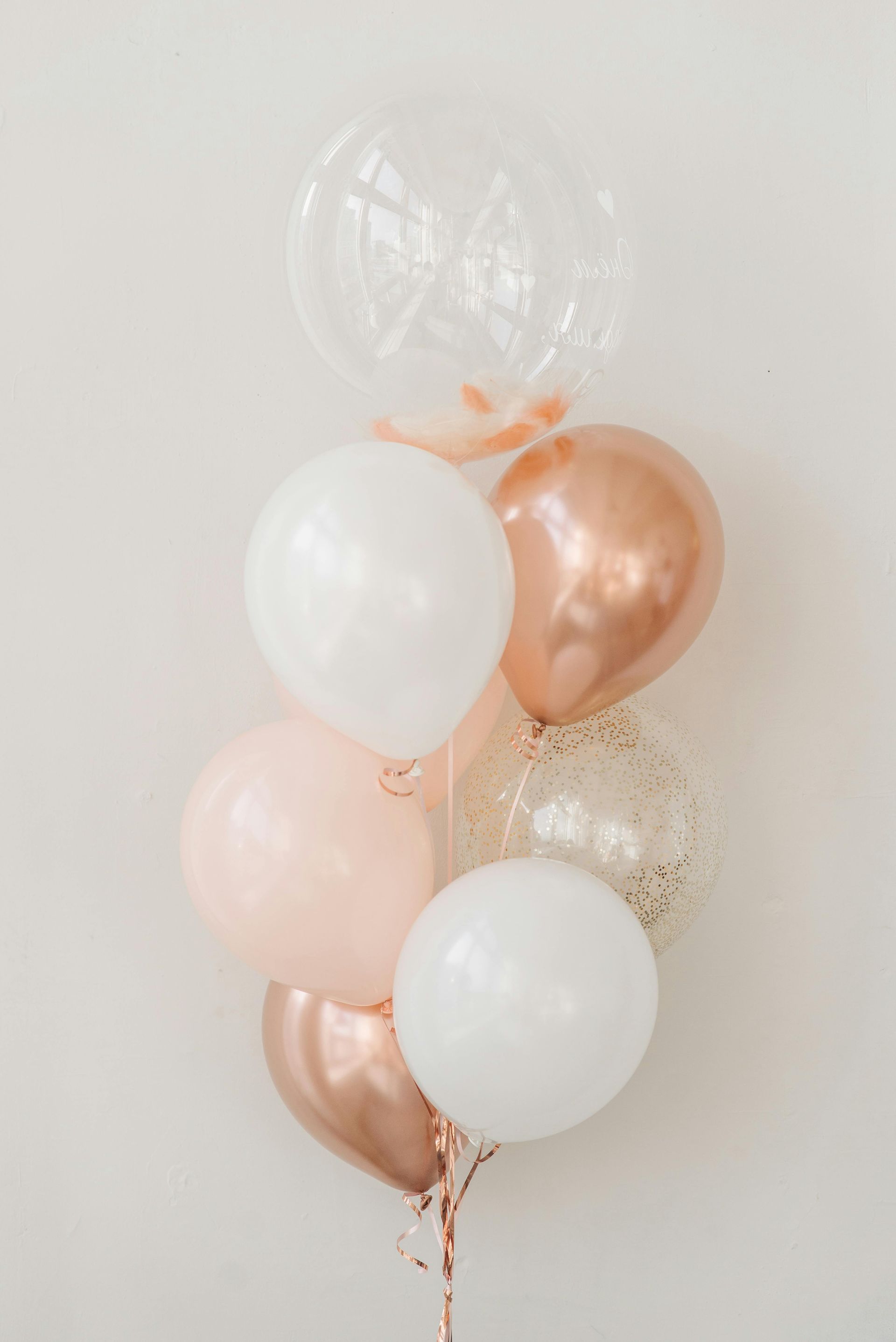 A bunch of balloons hanging from a string on a white wall.