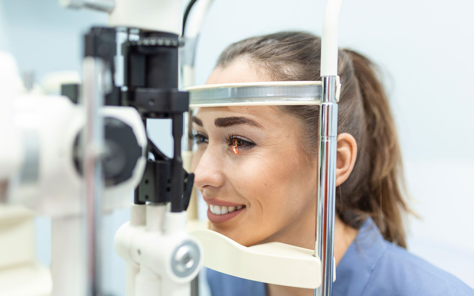 Woman having eye exam with a slit lamp machine. Smiling in a medical setting.