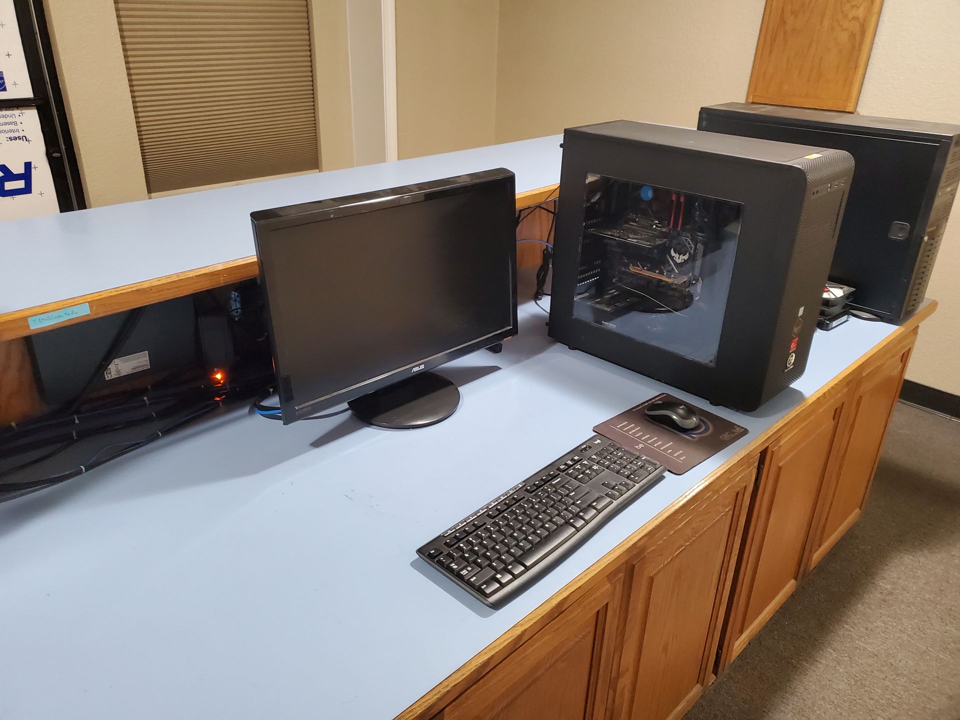 A computer is sitting on a desk next to a monitor and keyboard.