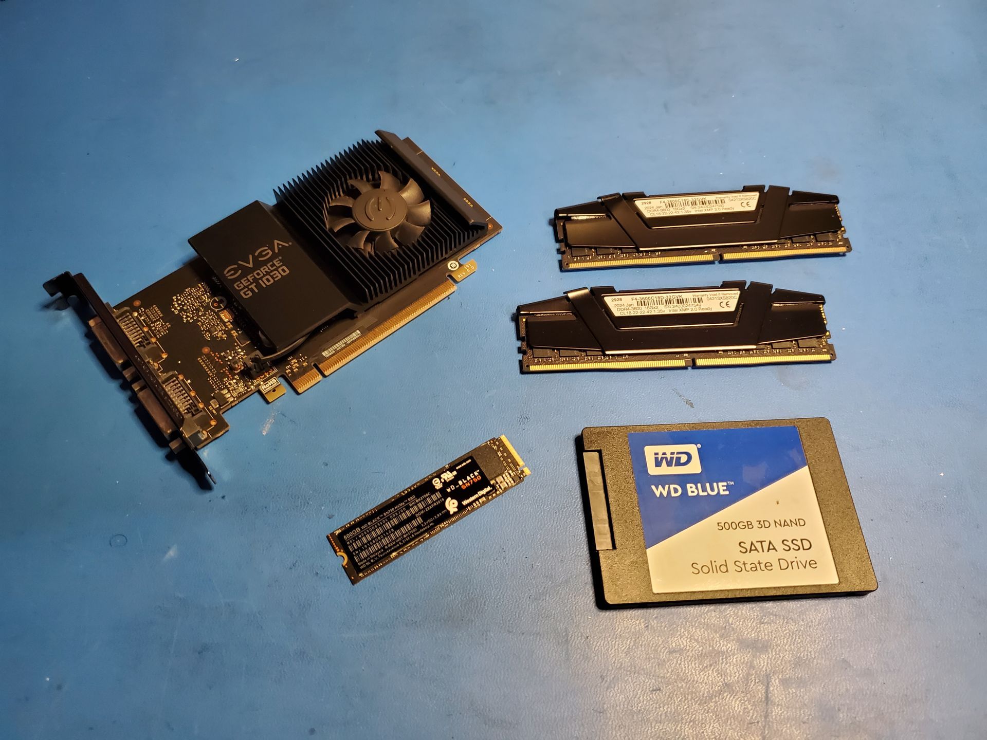 A graphics card , ram , and a ssd are sitting on a table.