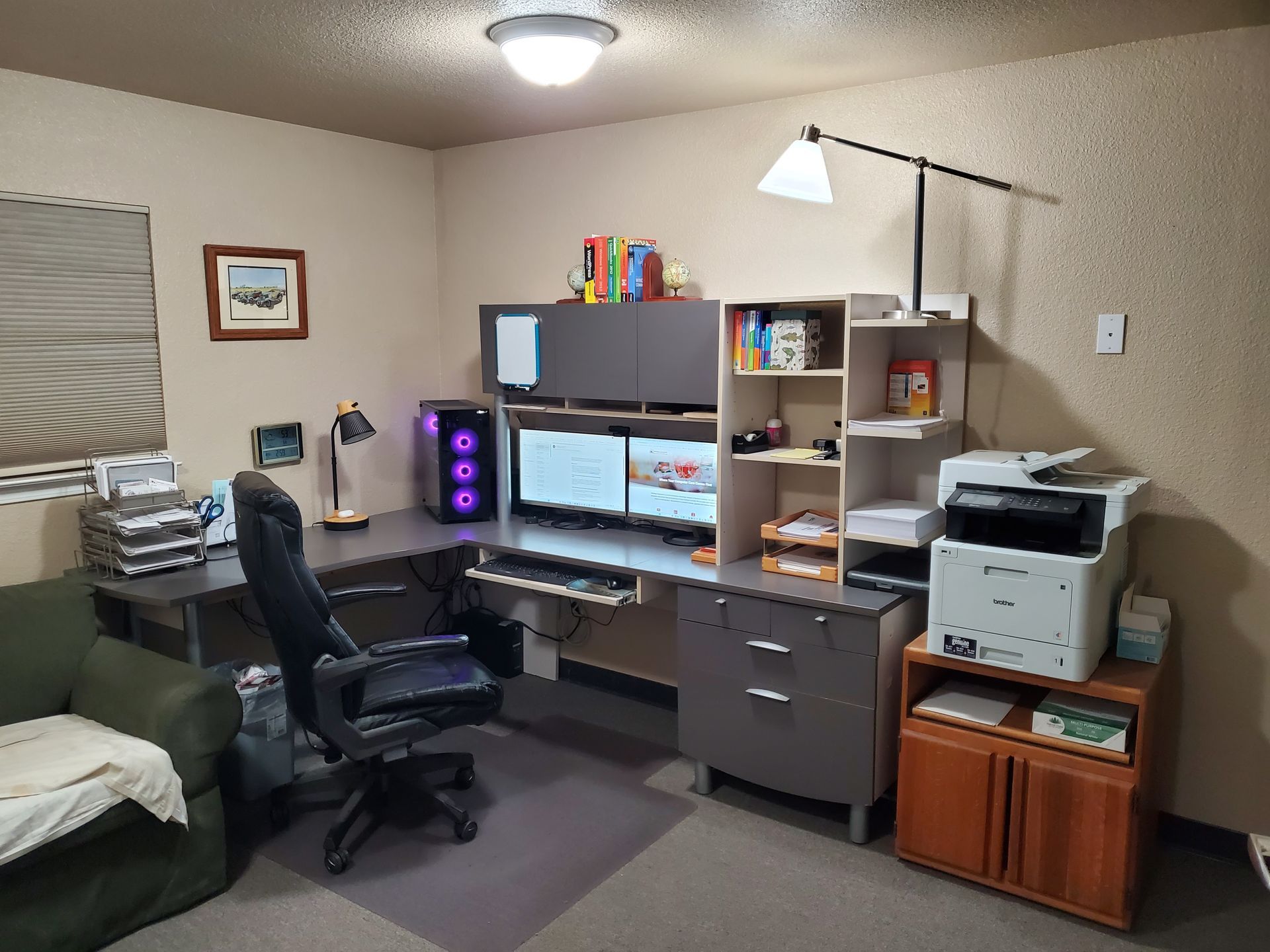 A room with a desk , chair , computer , printer , and shelves.