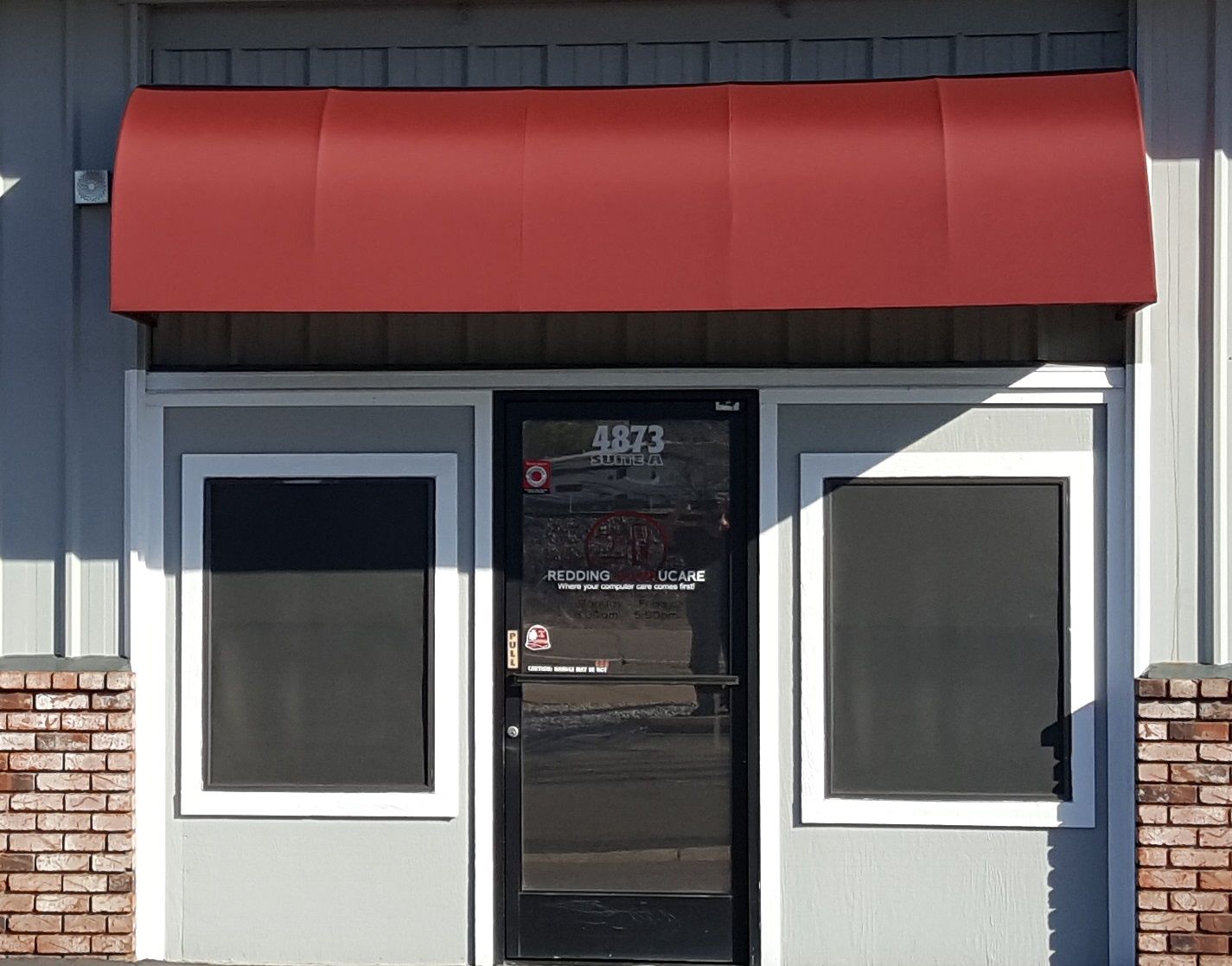 A store front with a red awning over the door