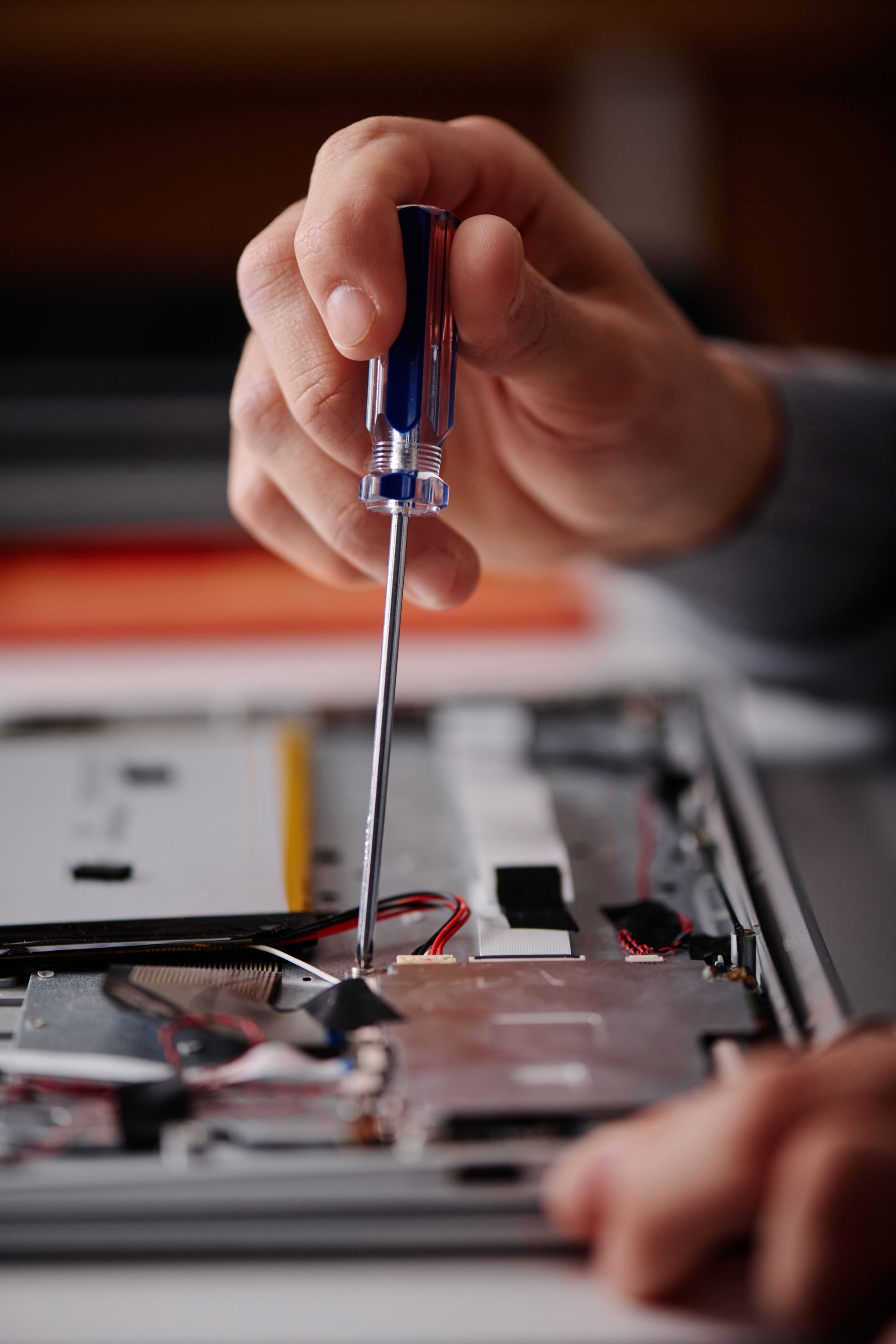 A person is fixing a laptop with a screwdriver.