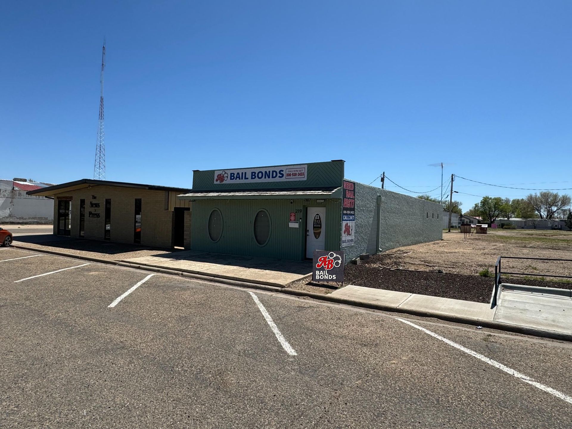 A small building is sitting on the side of the road next to a parking lot.