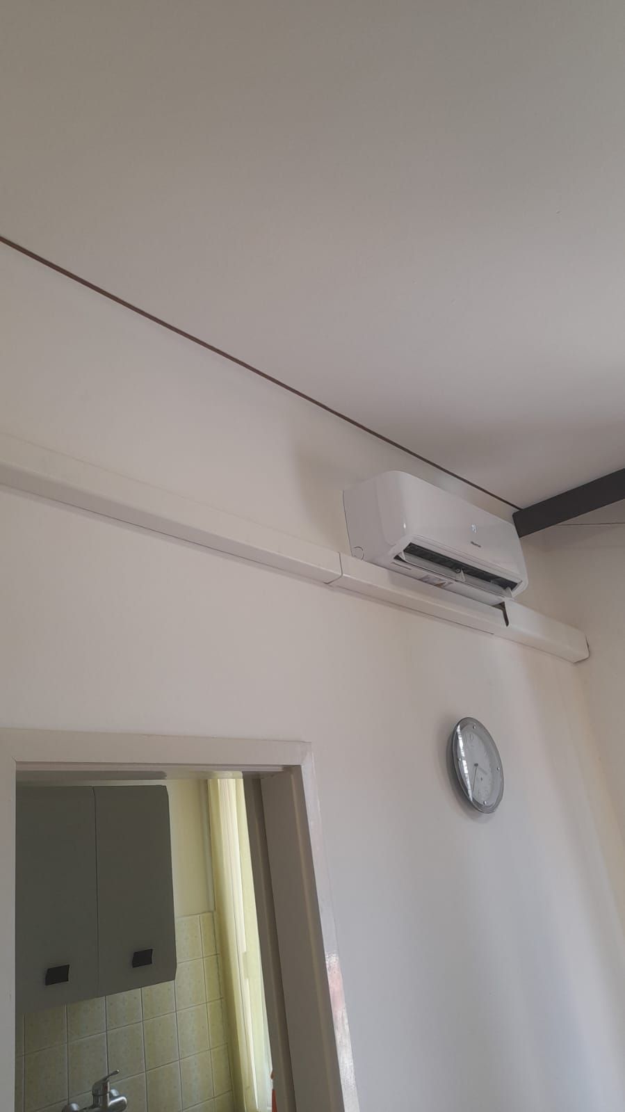 Una stanza con un orologio sul muro e un condizionatore d'aria montato a parete.