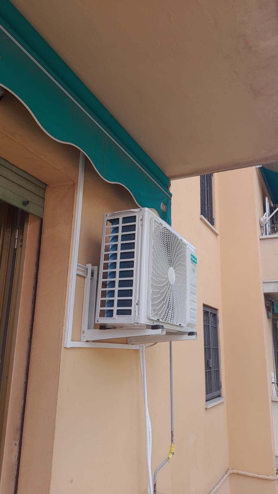 Un condizionatore d'aria è montato sul lato di un edificio sotto una tenda.