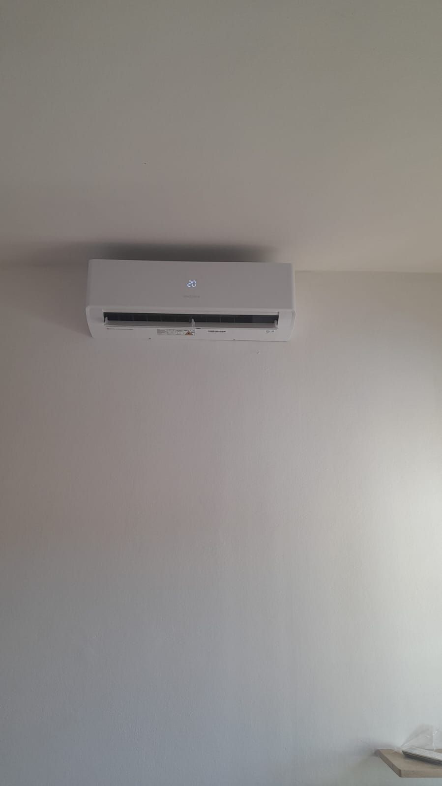Un condizionatore bianco è appeso a una parete bianca in una stanza.