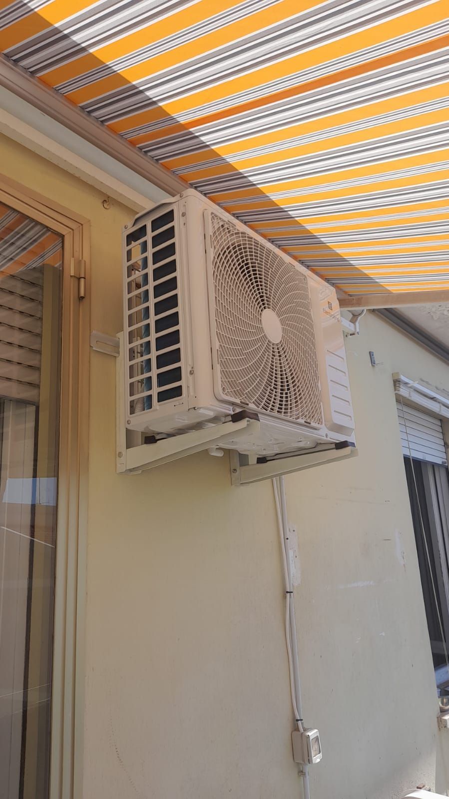Un condizionatore d'aria è montato sul lato di un edificio sotto una tenda.