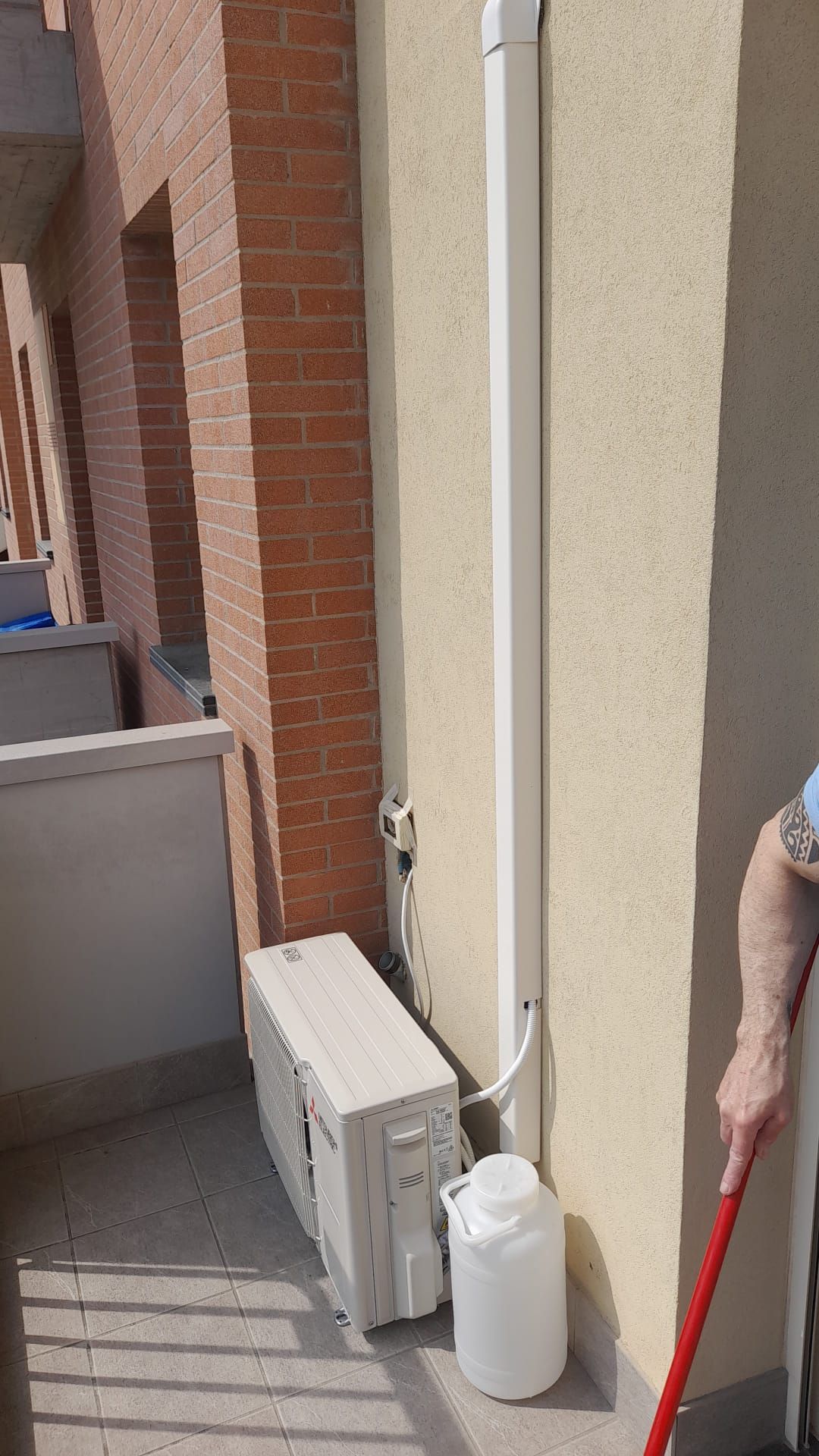 Un uomo è in piedi su un balcone con una scopa e una bottiglia d'acqua.