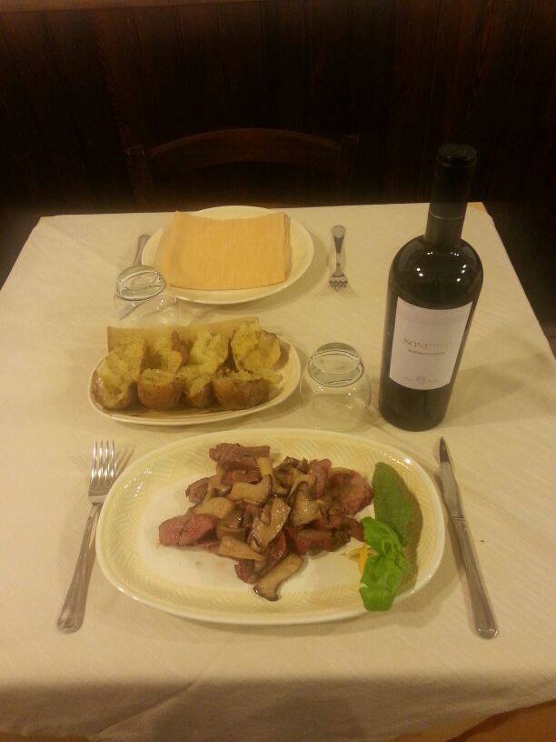 secondo piatto di carne con bottiglia di vino rosso