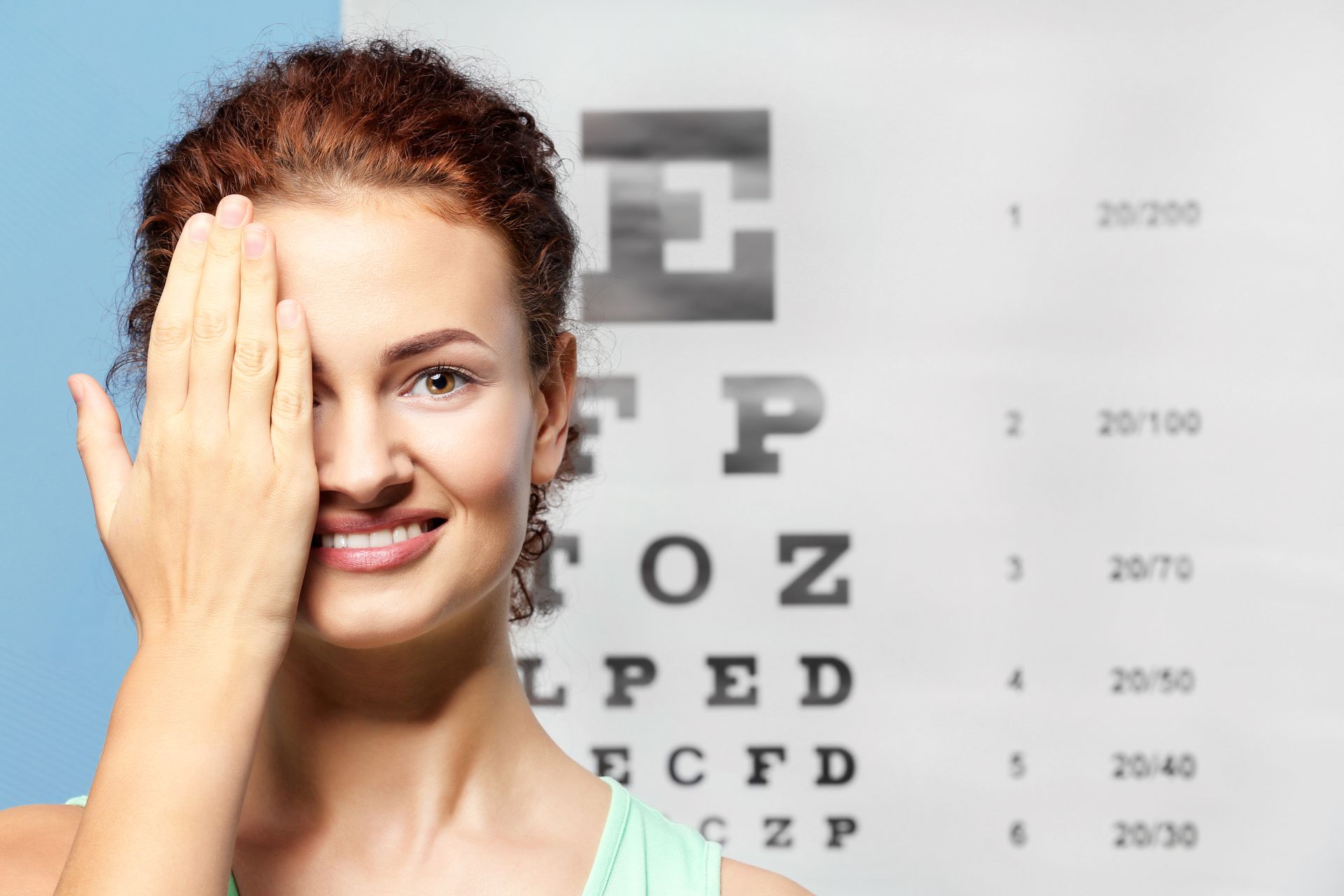 Woman covering one eye while viewing an eye chart at an eye exam clinic