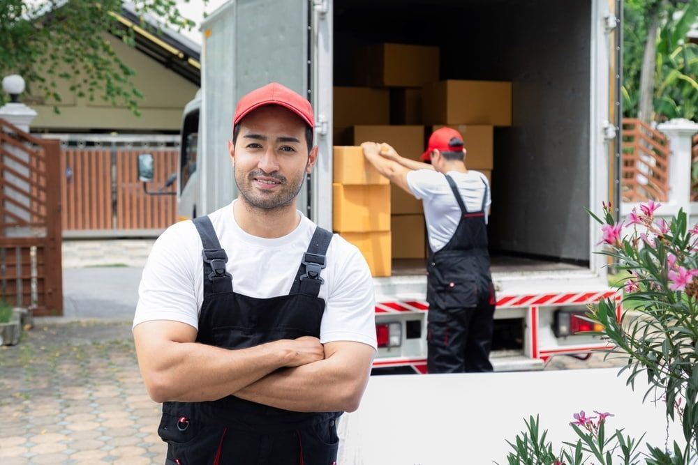A Man Is Standing In Front Of A Moving Truck With His Arms Crossed — Local & Country Removals in Newcastle, NSW