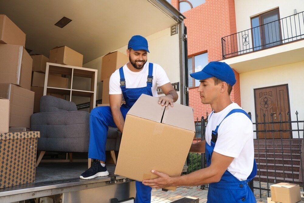 Two Men Are Carrying Boxes Out Of A Moving Truck — Local & Country Removals in Coffs Harbour, NSW