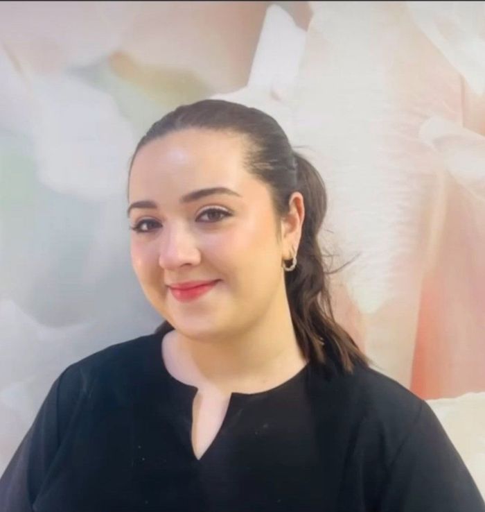 Woman with dark hair in a ponytail smiles.