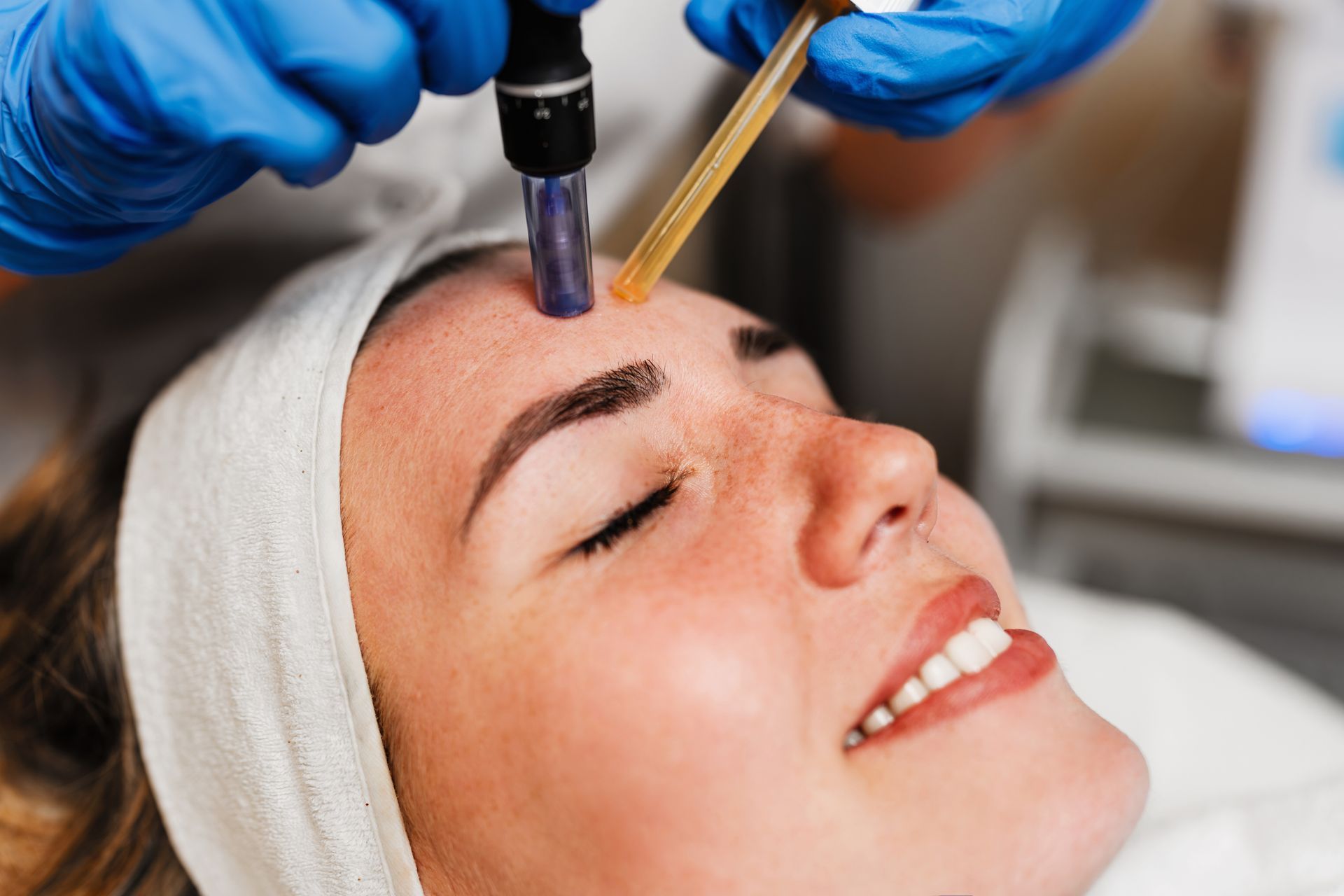 Facial treatment applying serum with a dropper on a woman’s forehead in a spa setting