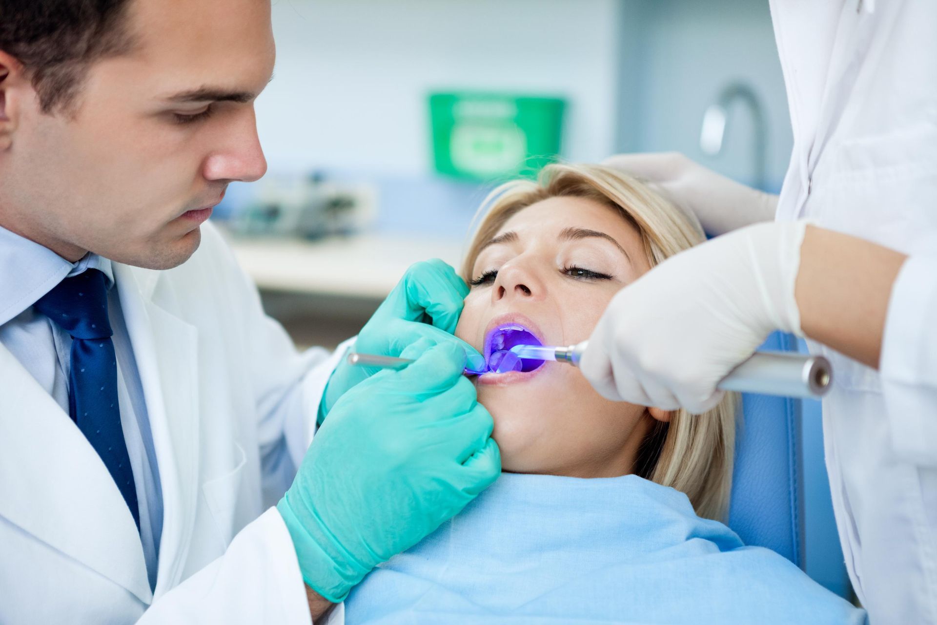 Dentist and assistant treating patient with purple mouth guard in a dental chair