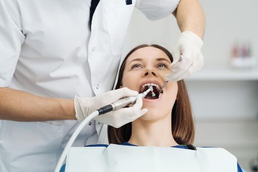 Dentist treating a patient with dental tools in a bright clinic, mouth open during examination