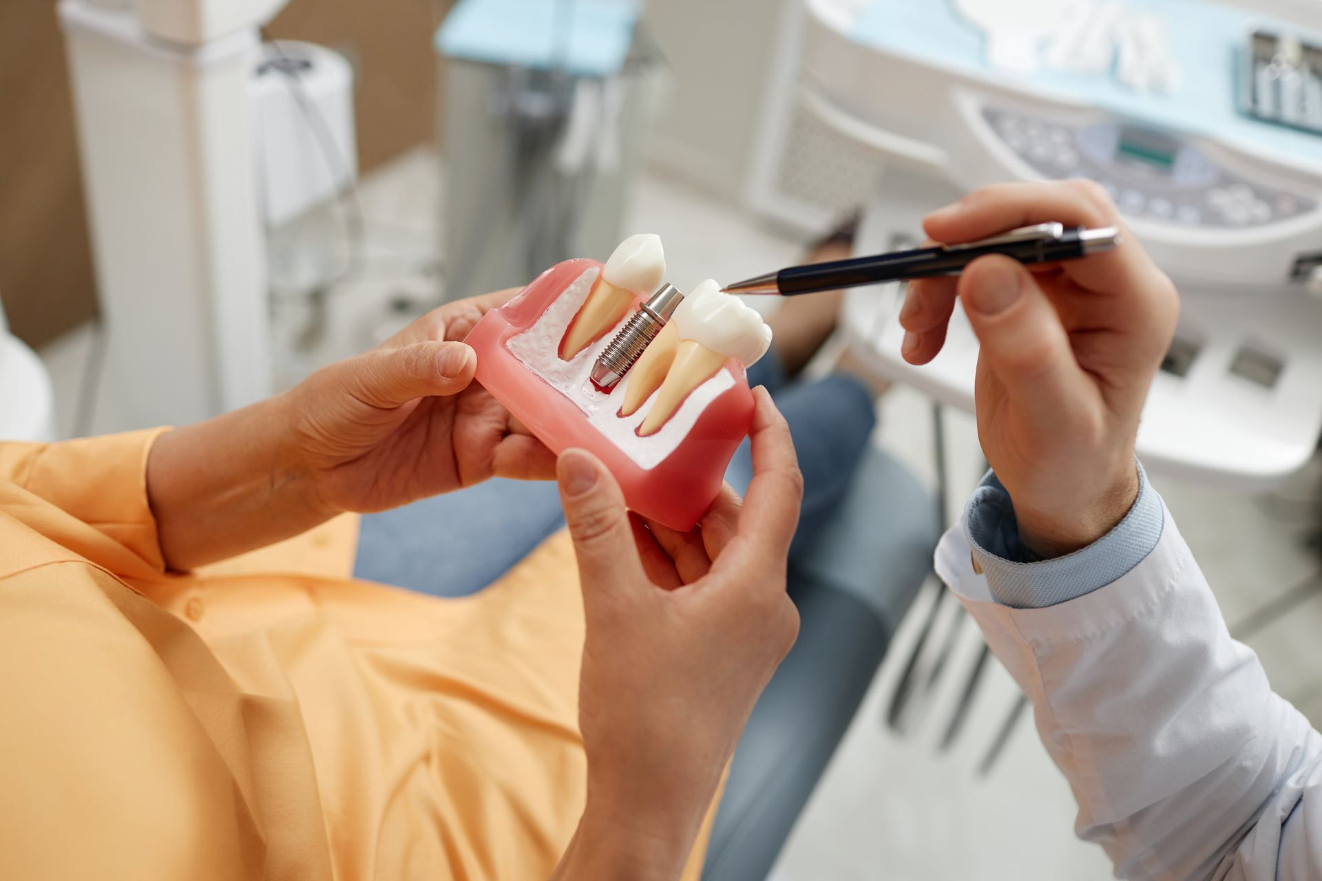 Dentist showing a tooth model to a patient with a dental tool in a clinic