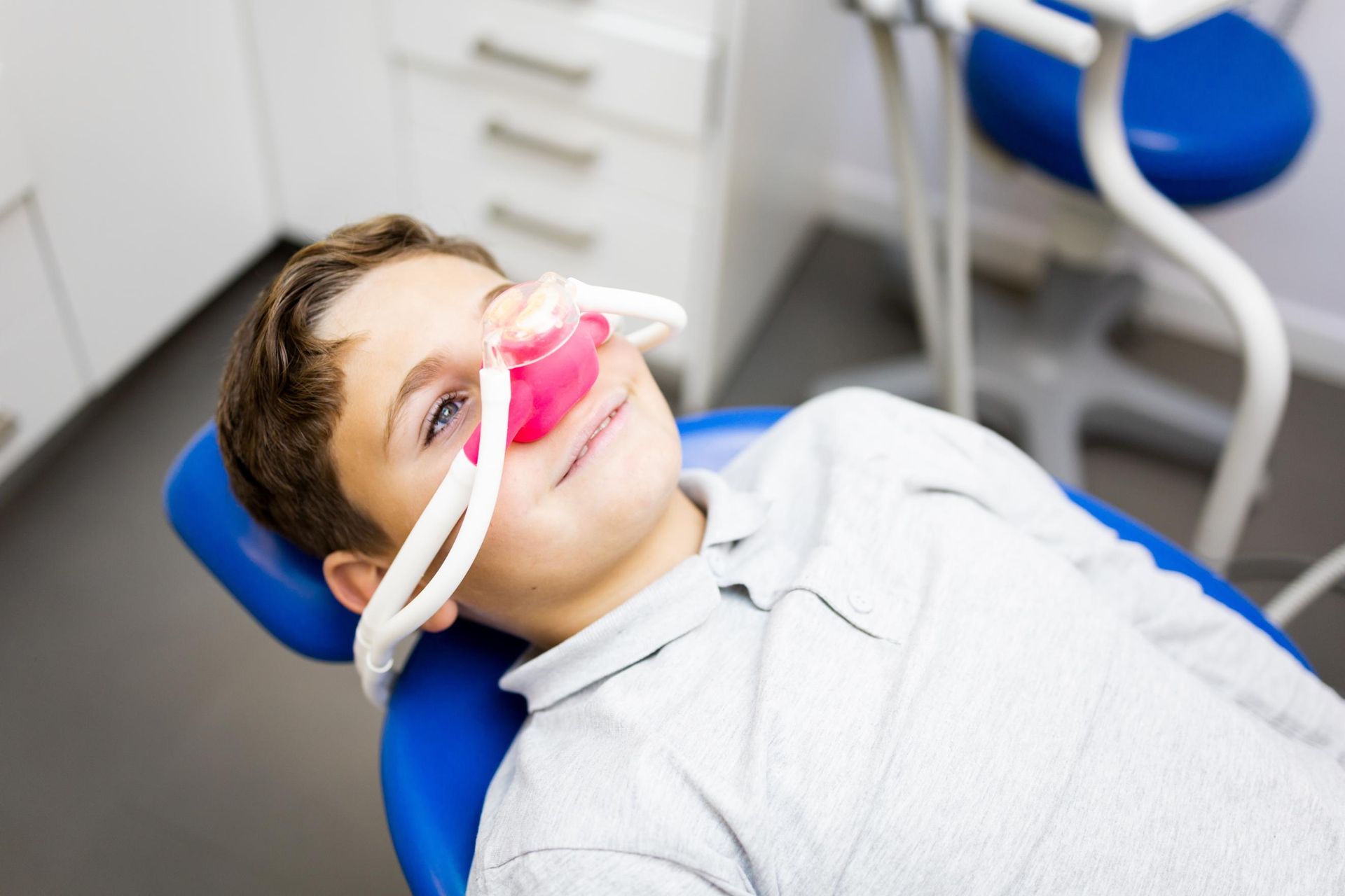 Patient reclined in dental chair with pink mouthguard during treatment in a clinic