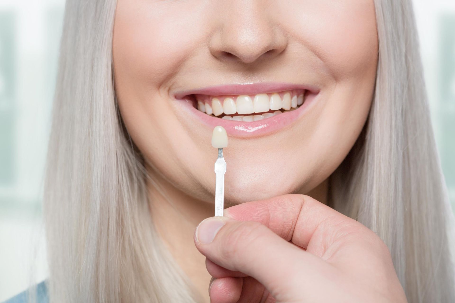Woman smiling while applying lip gloss with a wand