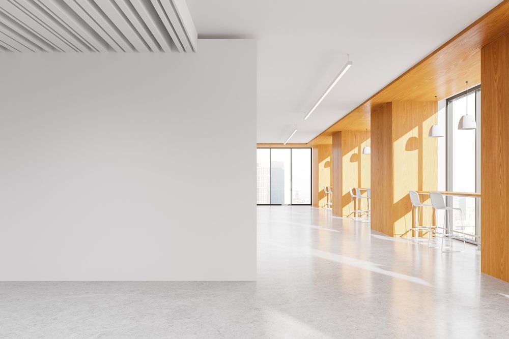 Modern office interior featuring a blank white wall, concrete floors, and a wood-paneled window seating area with stools. — George Pappas Painting In Buderim, QLD