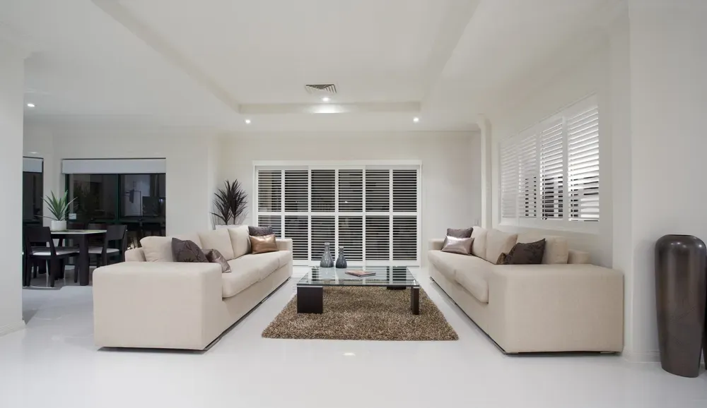 Modern White Living Room With Beige Sofas, Glass Coffee Table, and Large Windows — George Pappas Painting In Buderim, QLD