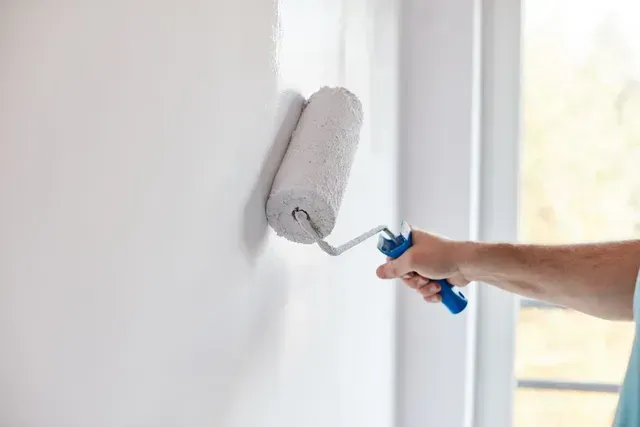 Person Using a Paint Roller, Applying White Paint to a Wall — George Pappas Painting In Buderim, QLD
