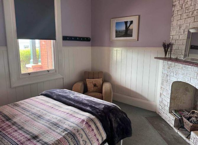 A bedroom with a bed , chair , fireplace and window.