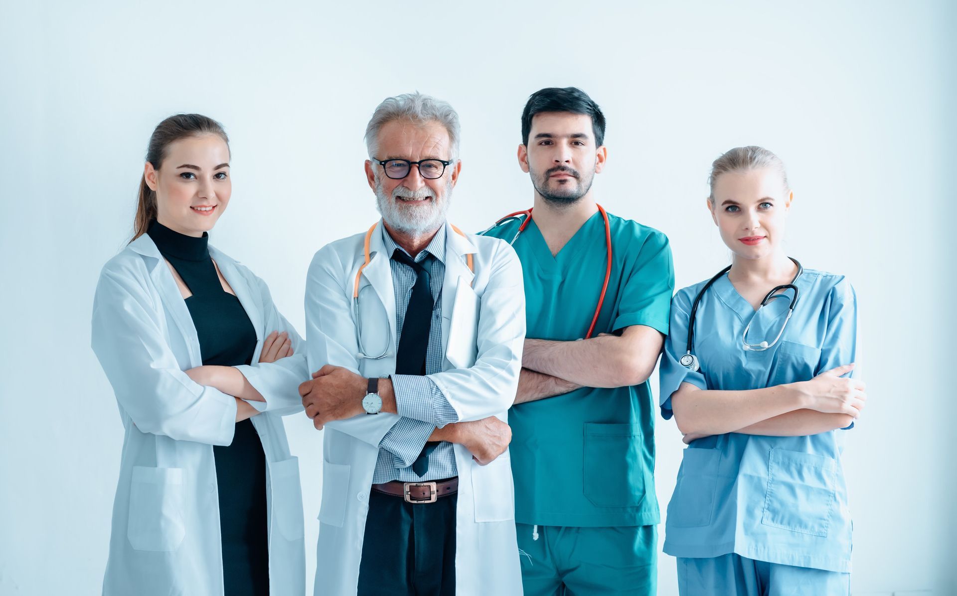 A surgeon is standing in an operating room with his arms crossed.