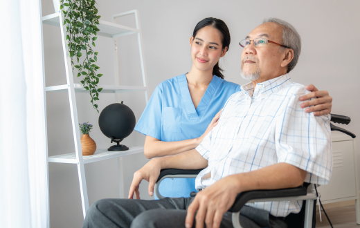 A doctor is writing on a clipboard in front of a patient in a hospital bed.
