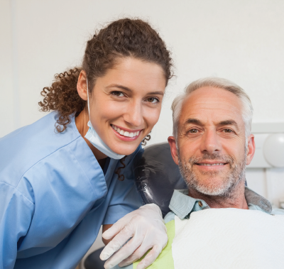 Dental hygienist and patient smiling together in a dentist's office.