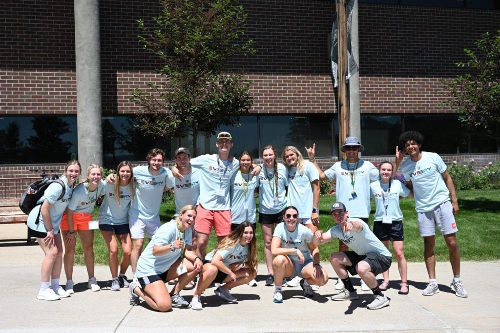 Group of people in matching blue shirts pose outdoors.
