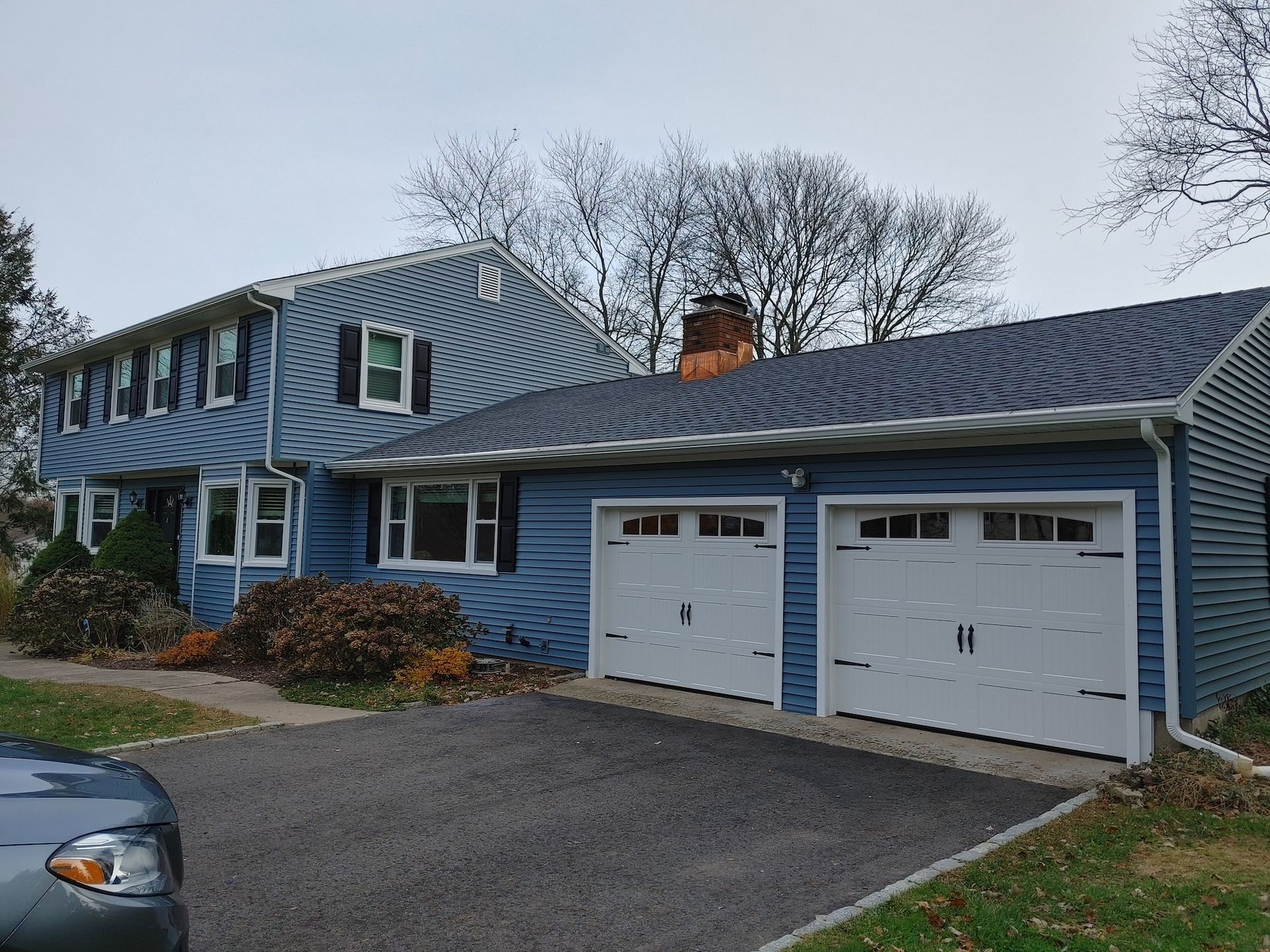 Blue two-story house with attached double garage and driveway on a cloudy day