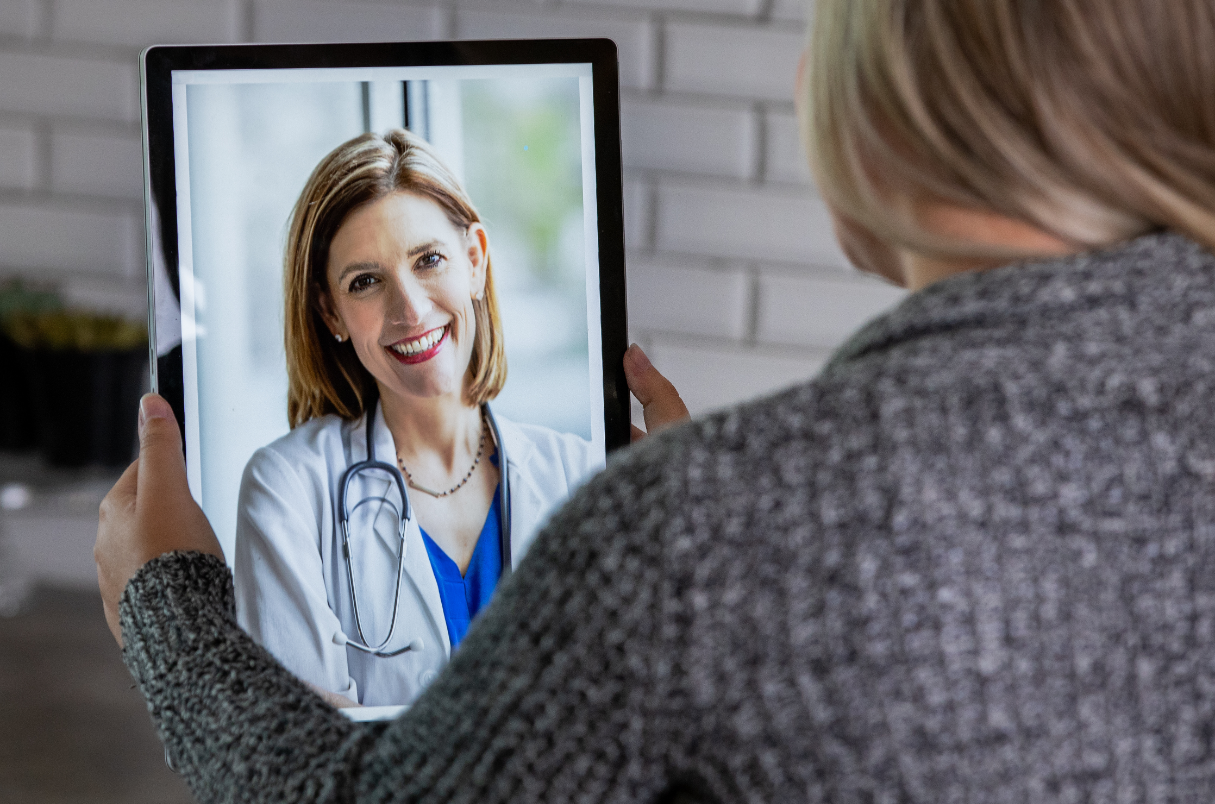 A woman is holding a tablet with a picture of a doctor on it.
