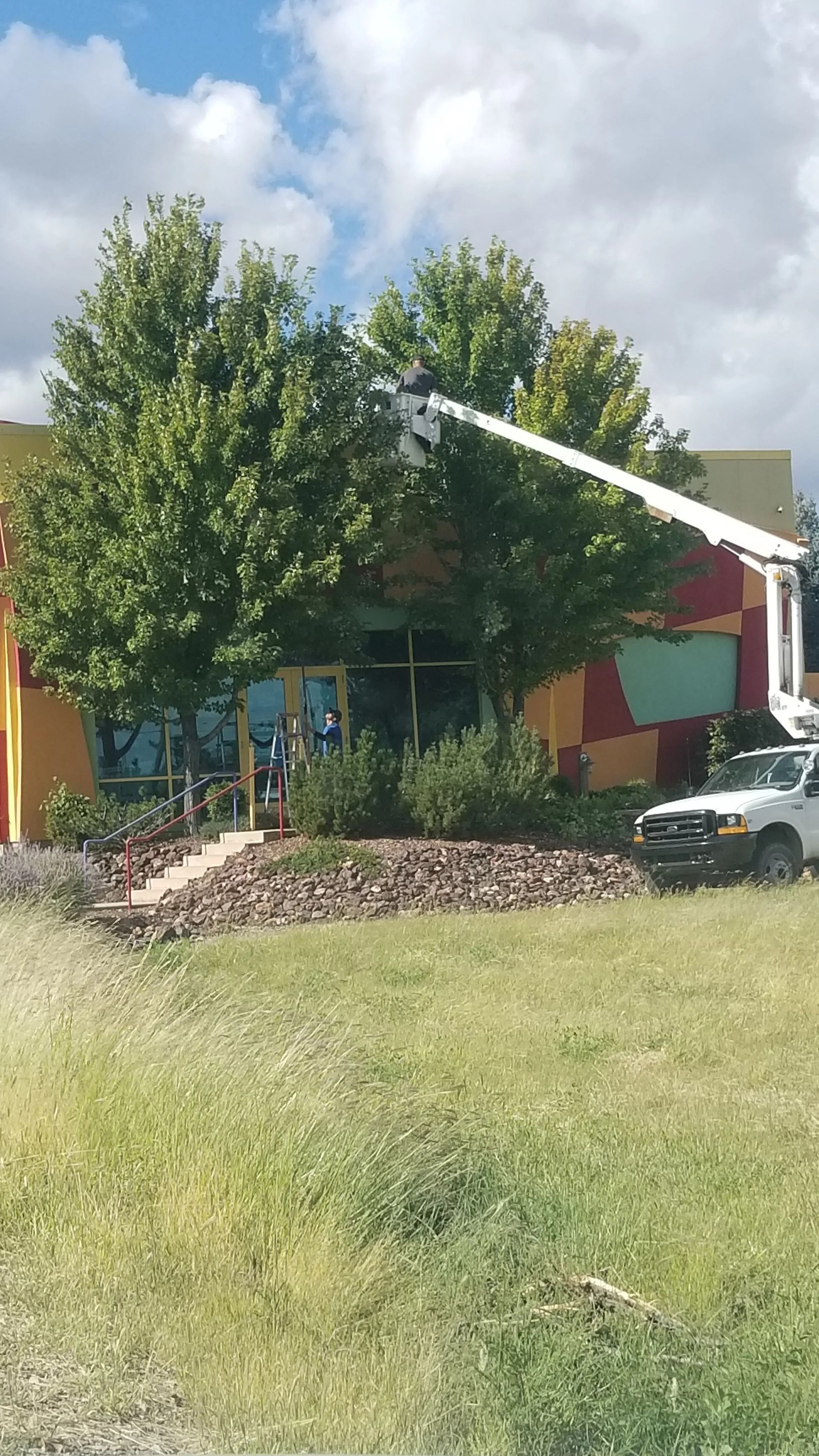 A white truck is parked in front of a building with a crane. A white truck is parked in front of a building with a crane.