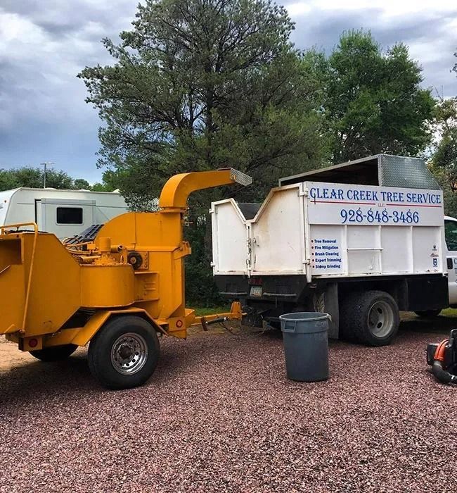 A clear creek tree service truck is parked next to a tree chipper