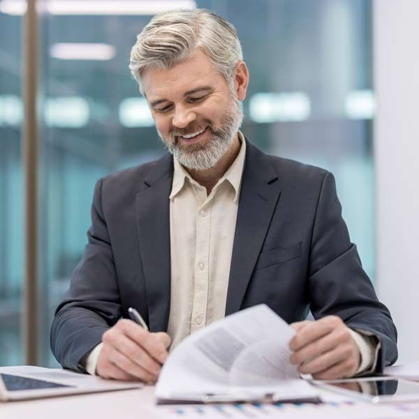Man in suit signing document at desk, smiling his content strategy has improved