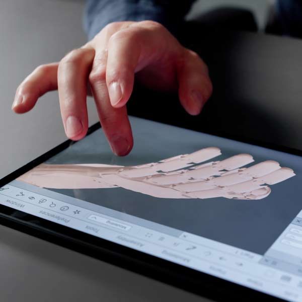 Biomedical Engineer touching a tablet screen displaying a 3D model of a hand.