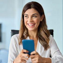 Woman Contacting Solution Web Designs Today for a Free Consultation and Learn How We Can Help You Grow Your Business. smiling, holding a blue smartphone, in an office setting.