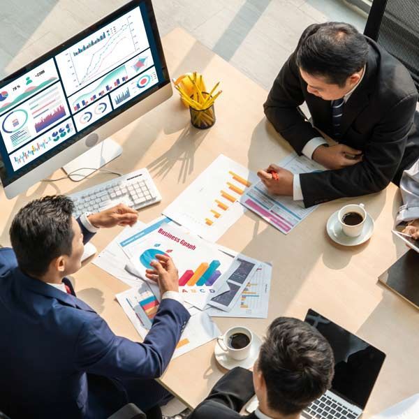 Social Media strategists reviewing charts and data during a meeting, with a computer and papers on a table.