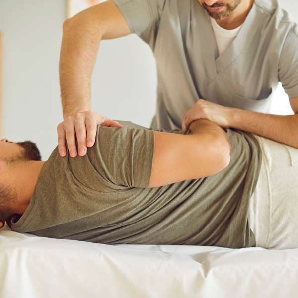 A person receiving a back massage from a chiropractor, lying on a massage table.