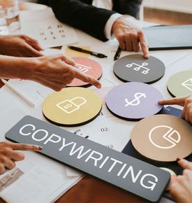 Hands pointing at circular icons on a table, including a dollar sign, with a 