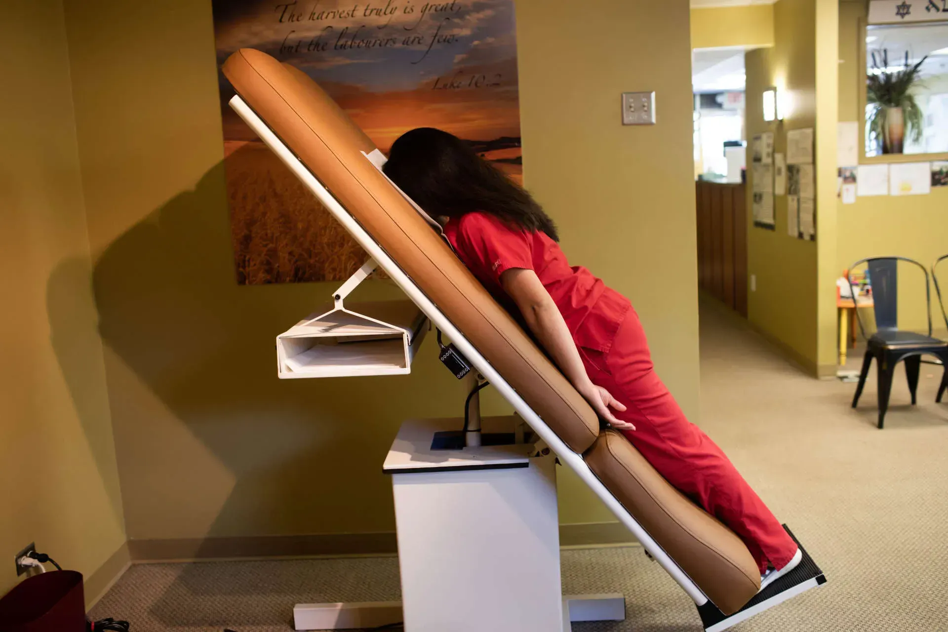 Person using a slanted scan table in a clinic, leaning forward during the procedure.