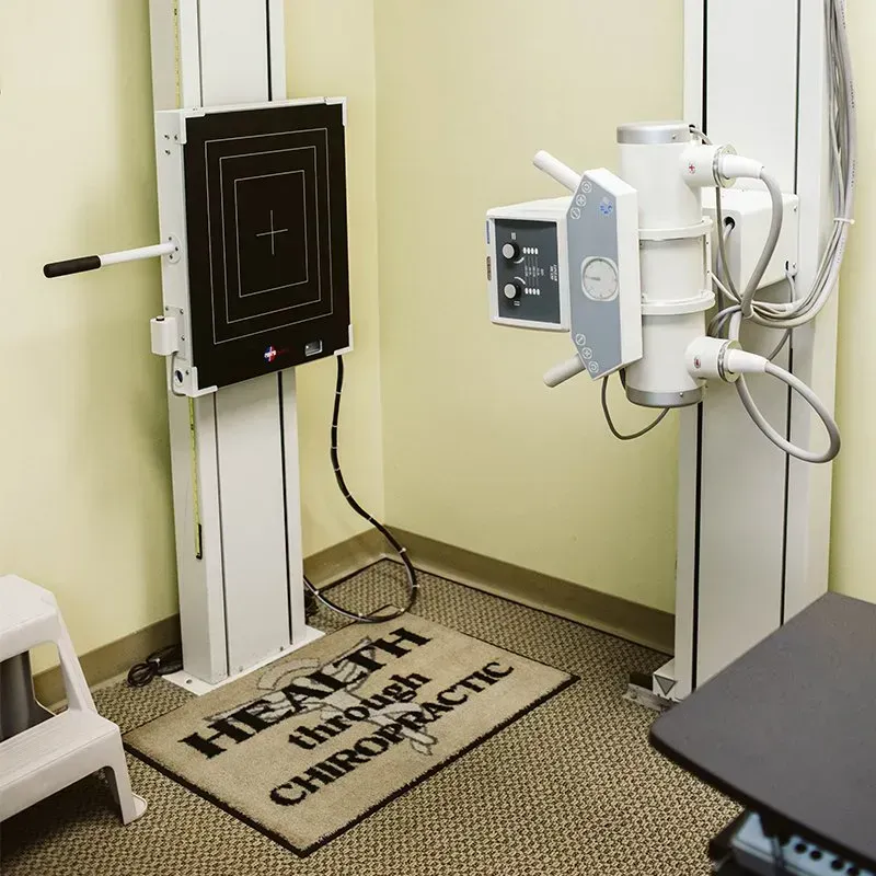 Ultrasound imaging room with medical equipment and a “Health Through Chiropractic” floor mat