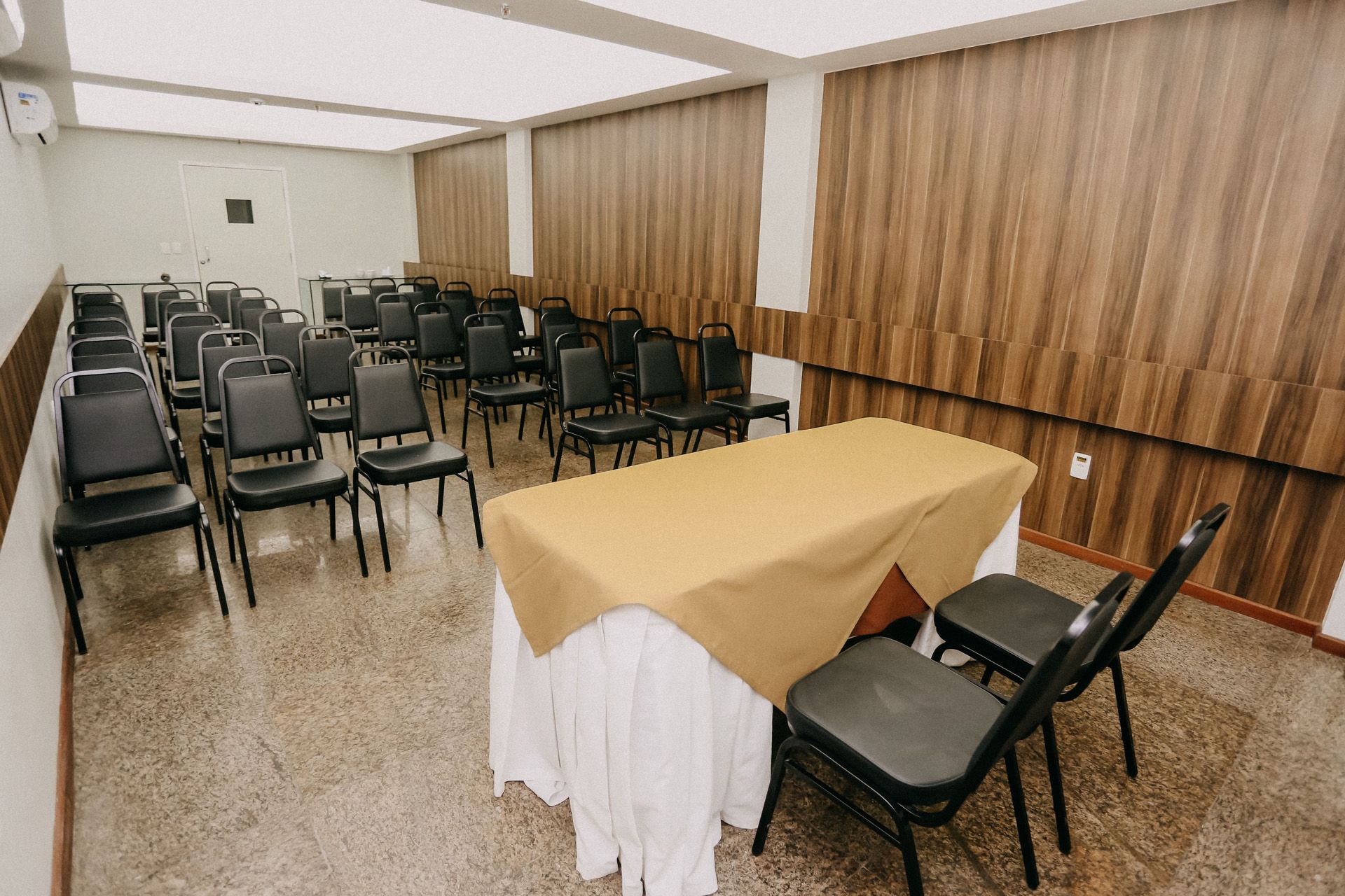 Buffet de café da manhã com diversos itens alimentares: pães, bolos, frutas e pratos quentes, em um refeitório.