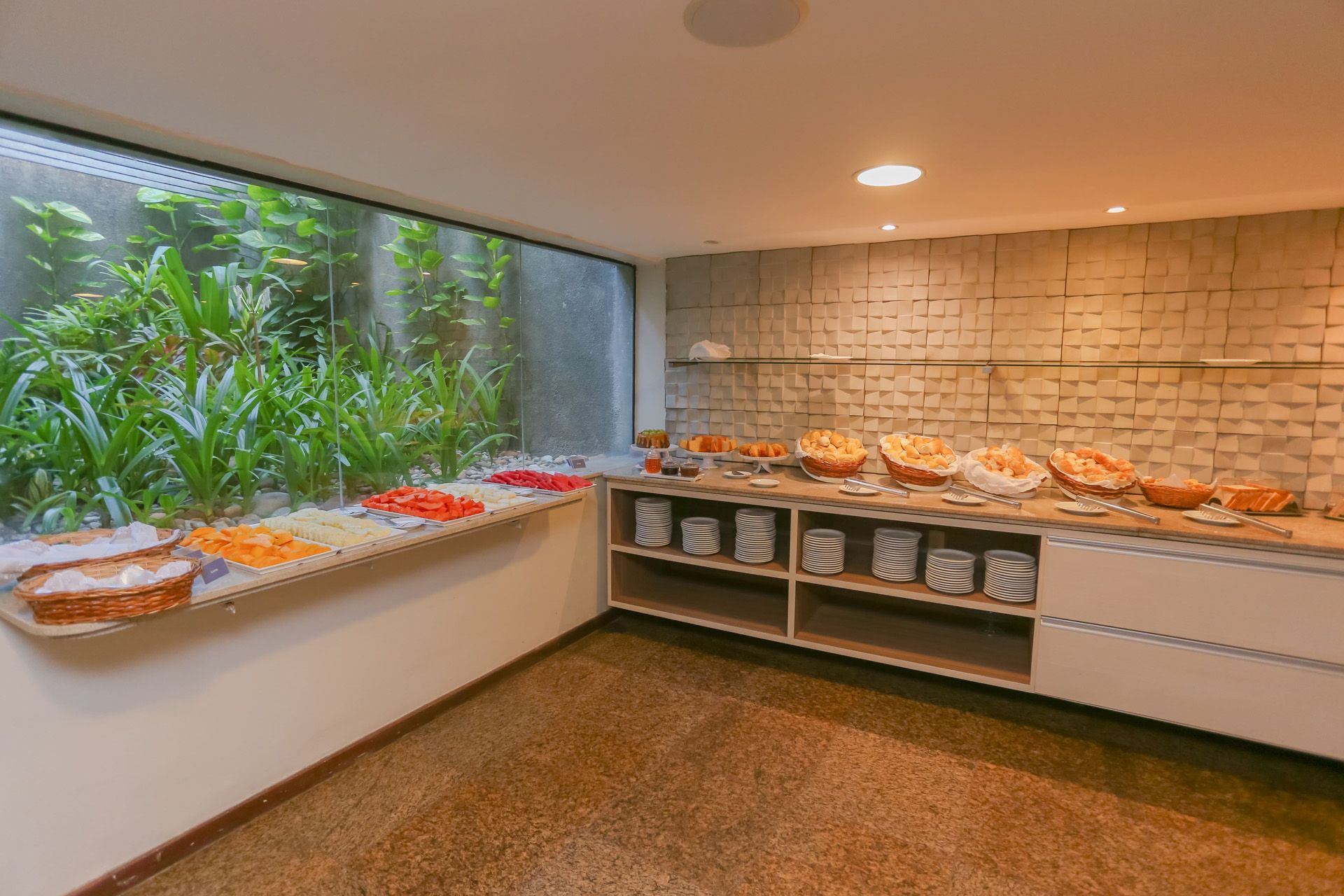 Mesa de café da manhã posta com ovos mexidos, bebidas e doces em um ambiente de restaurante.