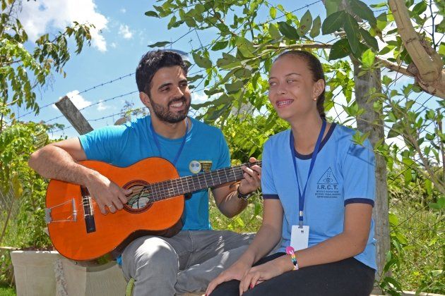 Um homem está tocando violão ao lado de uma mulher