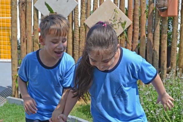 Um menino e uma menina estão parados um ao lado do outro em frente a uma cerca de madeira.
