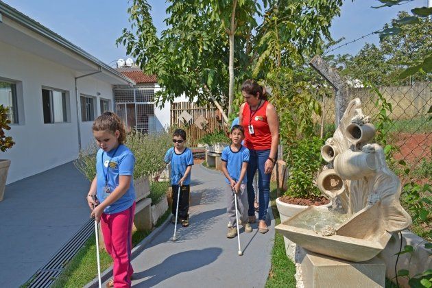 Um grupo de crianças está caminhando pela calçada com bengalas.